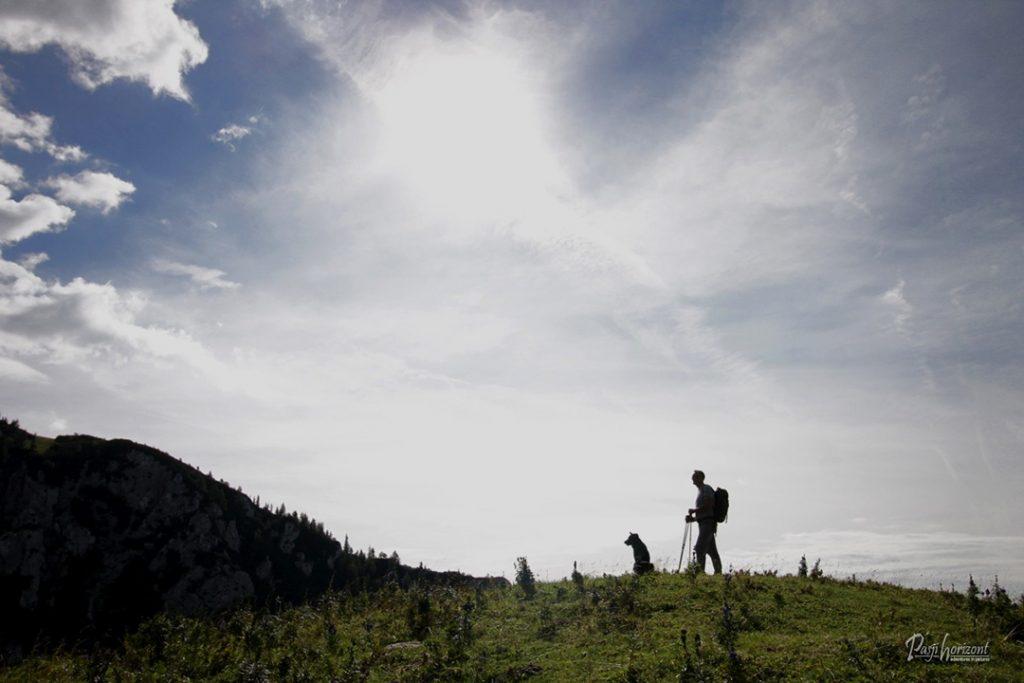 Travnat greben na poti proti Planini Koren s silhuetama planincev