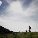 Travnat greben na poti proti Planini Koren s silhuetama planincev