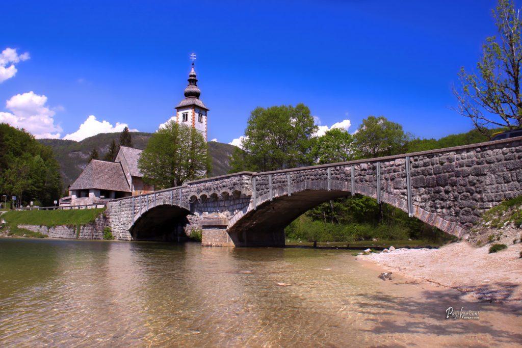 Most čez Bohinjsko jezero s cerkvijo sv. Janeza Krstnika v ozadju
