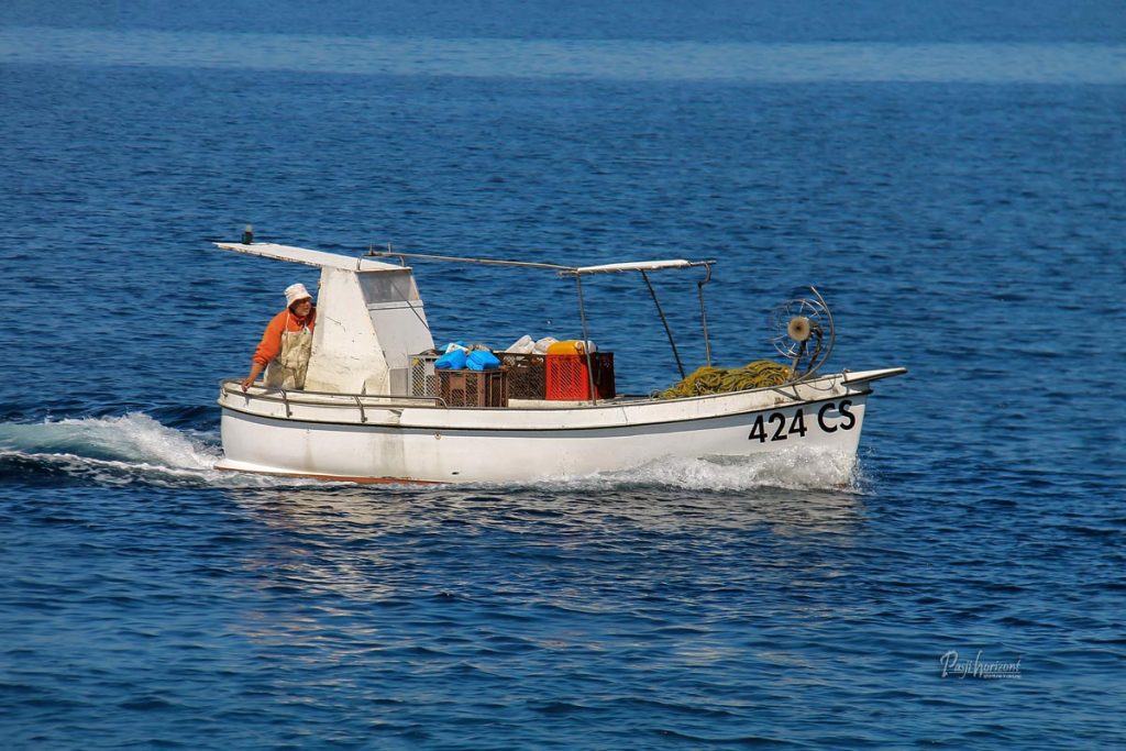 Majhna ribiška barka na morju, z ribičem na krovu