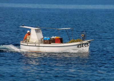 Majhna ribiška barka na morju, z ribičem na krovu